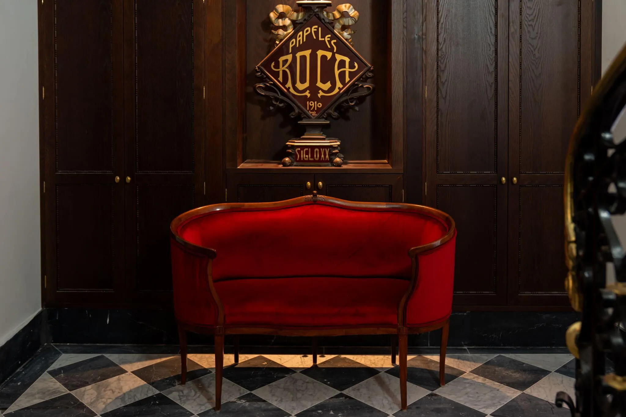 Red velvet sofa below the Papeles Roca sign in the lobby of Casa Roca boutique hotel in Palma Old Town
