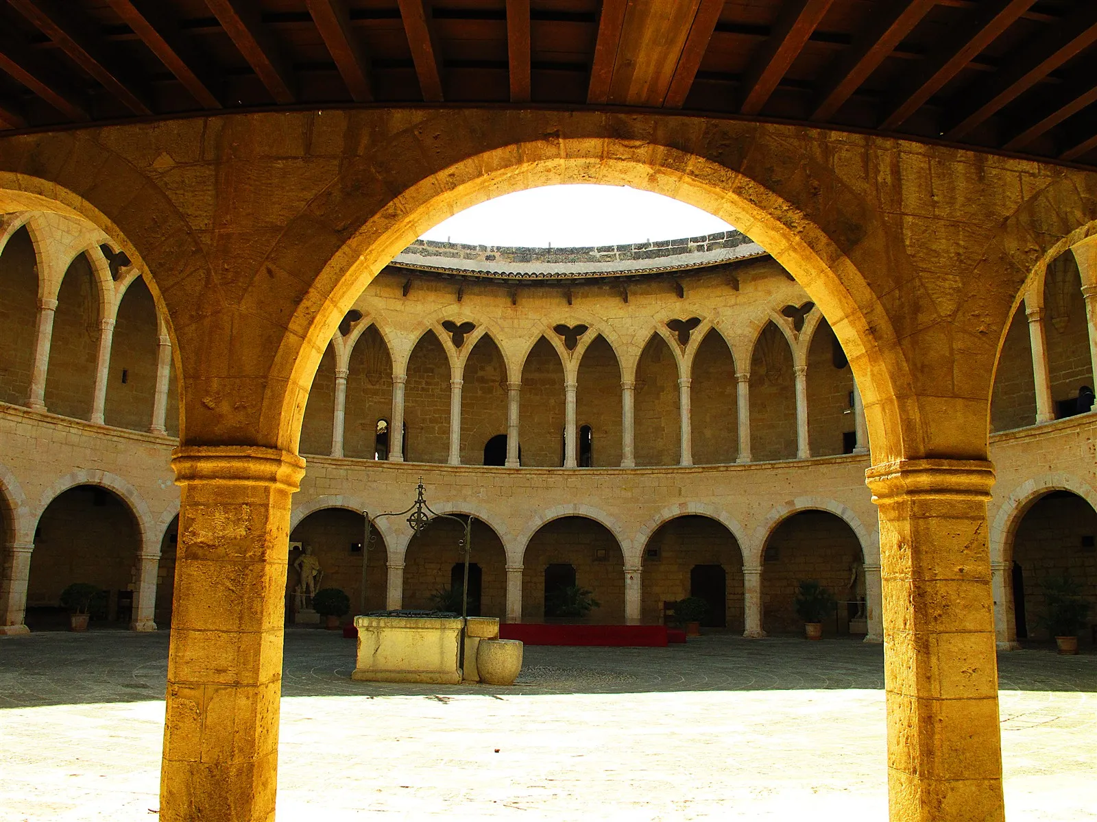 Gothic arcade arches framing the courtyard and well at Bellver Castle, Palma