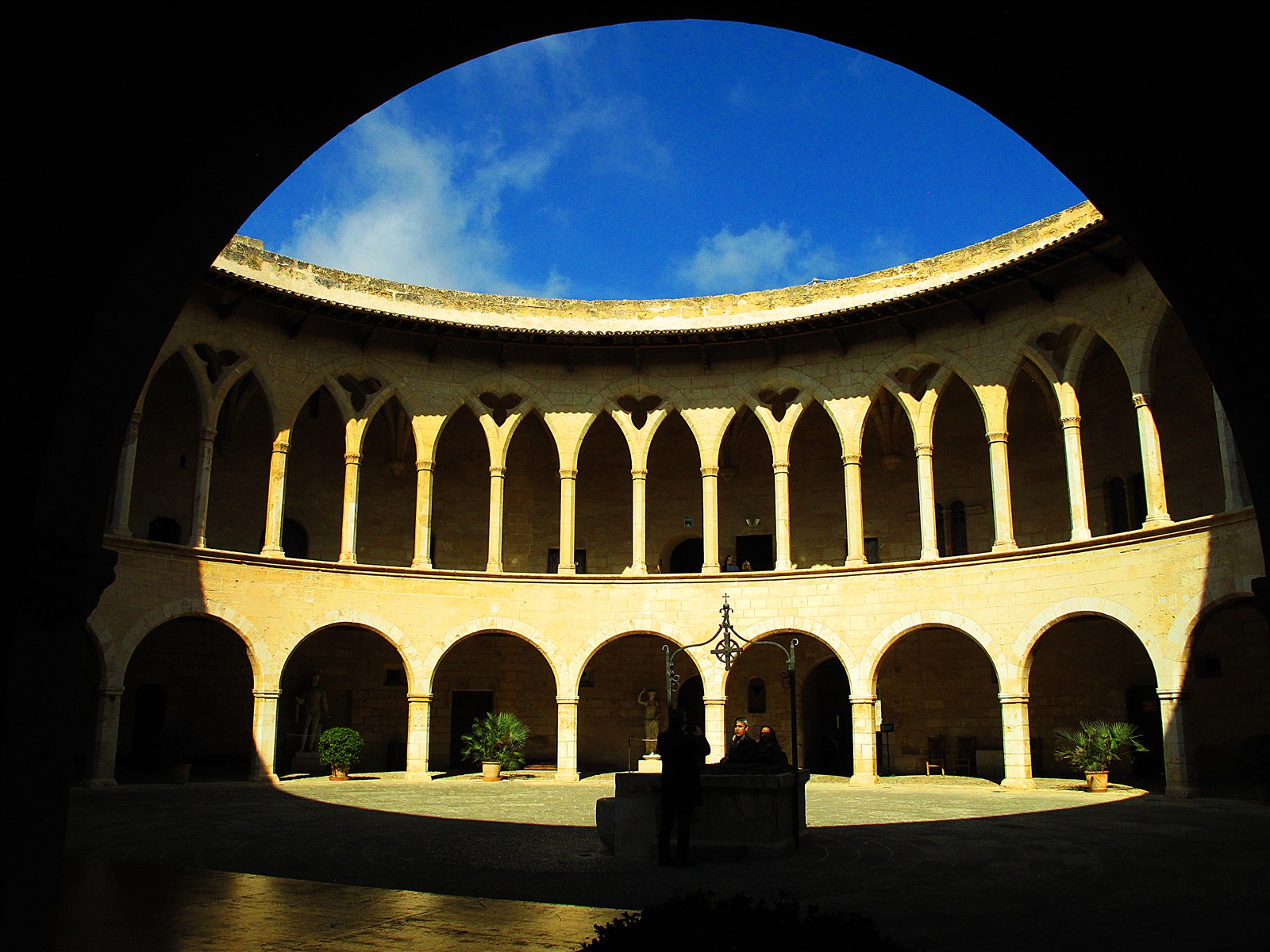 The courtyard of Bellver Castle framed by a stone arch in shadow