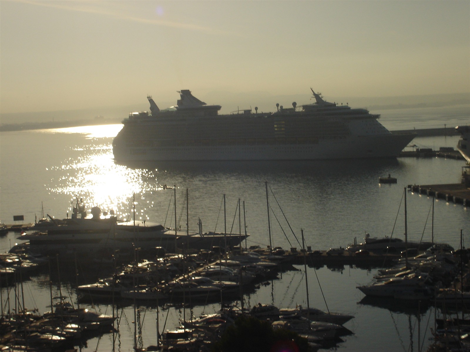 Cruise ship berthed at Palma de Mallorca port at sunrise with yachts in the marina below