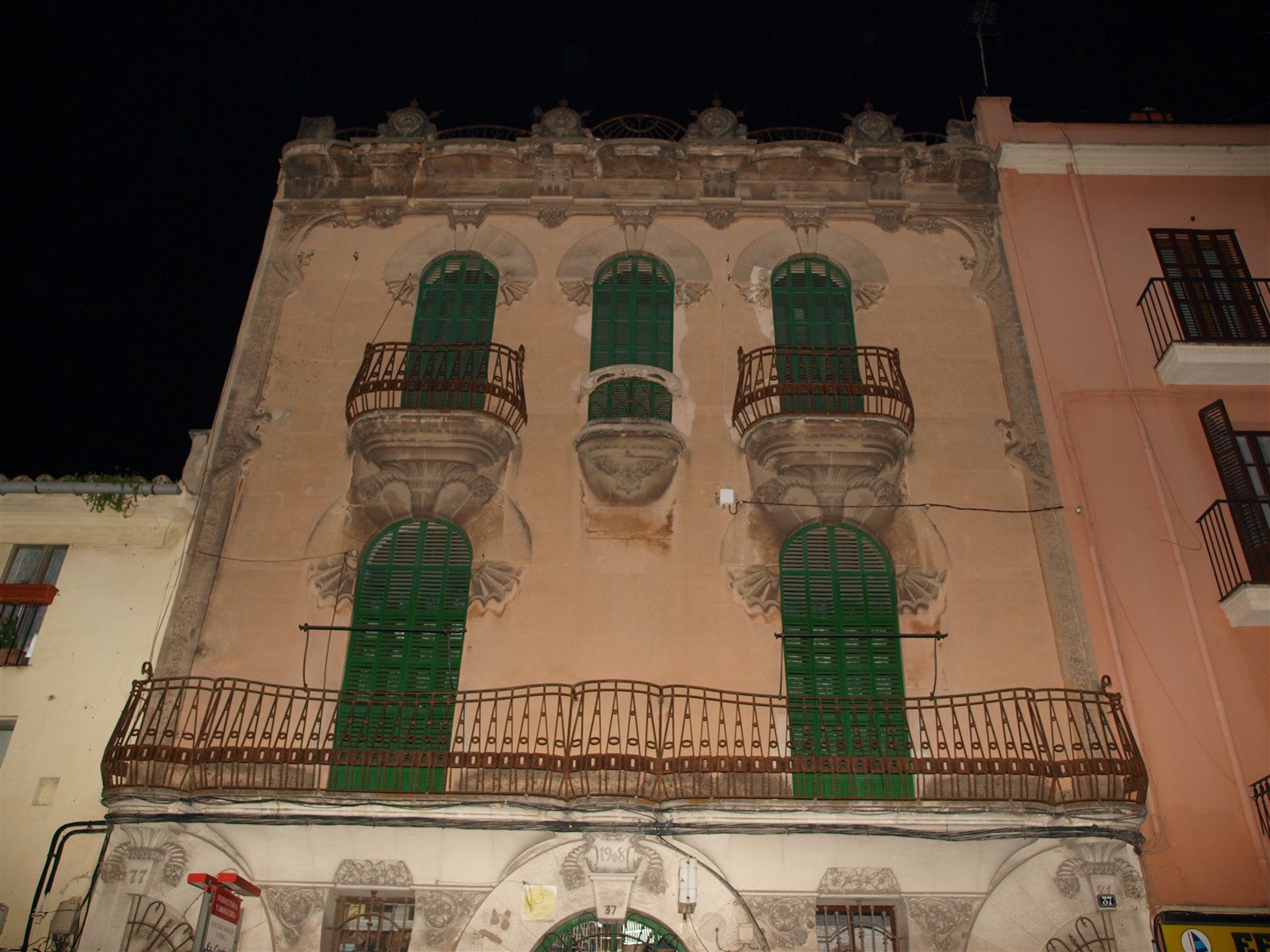 A modernist facade with green shutters and iron balconies in Santa Catalina, Palma